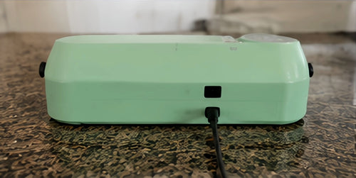Mint green compact vacuum sealer rear view with power connection